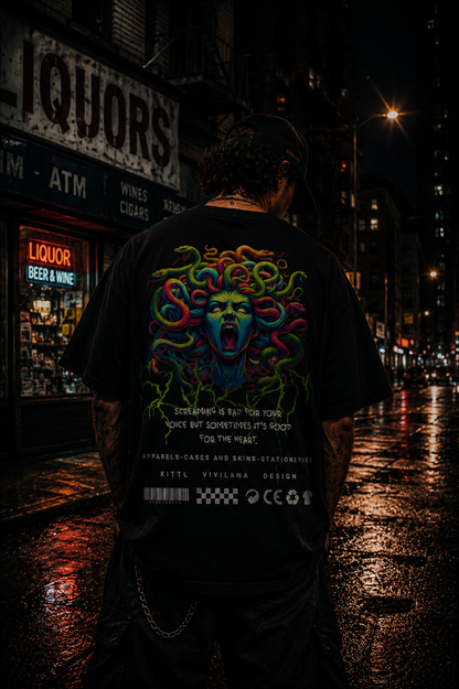 Man wearing black graphic tee with colorful Medusa design, urban night street backdrop, bold streetwear style