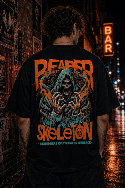 Black graphic tee with grim reaper skeleton design, bold orange text, worn on city street at night
